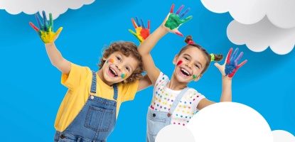 Two smiling children with painted hands against a bright blue sky with clouds 